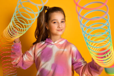 Teen girl play rainbow slinky toy on color background