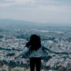 Rear view of woman standing on landscape against sky