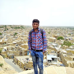 Portrait of young man standing against cityscape