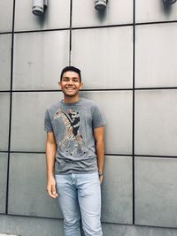 Portrait of smiling young man standing against wall