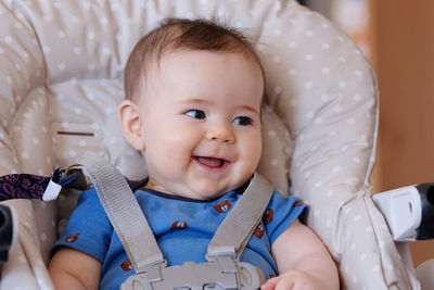 Beautiful baby boy is smiling in a high chair