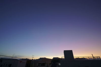 Low angle view of silhouette buildings against blue sky