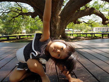 Close-up of cute girl sitting on plank in park