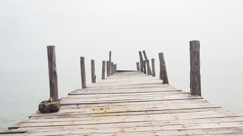 Wooden pier on sea against sky