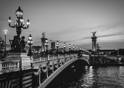 Arch bridge over river against sky in city