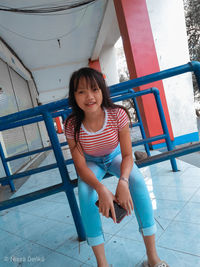 Portrait of smiling girl sitting on tiled floor