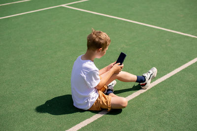 A boy on the street writes a text message on his phone