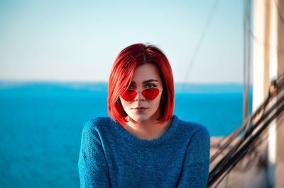 Portrait of young woman wearing sunglasses against sea