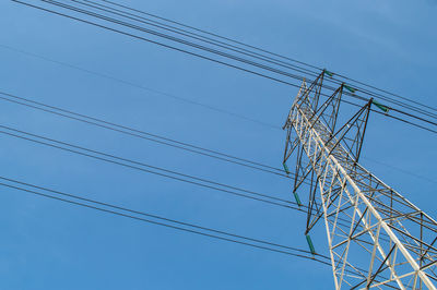 Low angle view of electricity pylon against blue sky