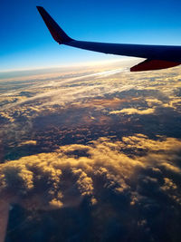 Aerial view of airplane wing against cloudy sky
