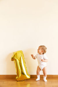 Full length of cute baby girl on wall at home