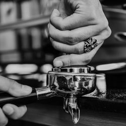 Cropped hands of person holding porta filter in cafe