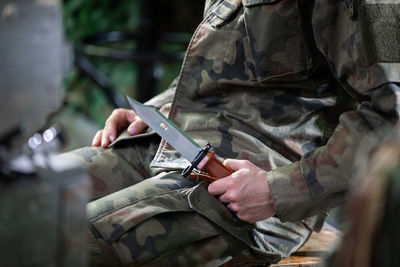 A military lady in a moro uniform sits on a chair with a bayonet in her hand. 