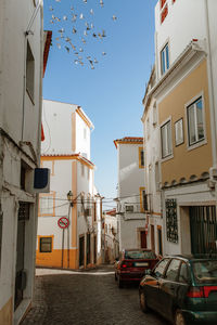 Cars on street amidst buildings in city against sky