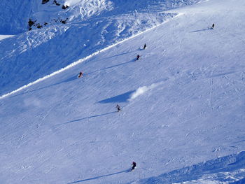 People skiing on snowcapped mountains during sunny day