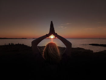 Rear view of silhouette woman at beach during sunset