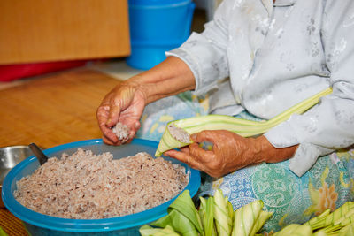 Hands of senior woman wrapping the sticky rice with palm leaf or ketupat palas