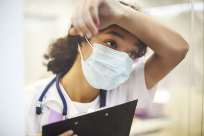 Nurse wearing mask while holding clipboard at clinic