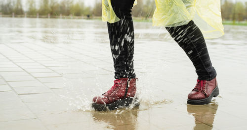 Low section of woman standing in water on footpath