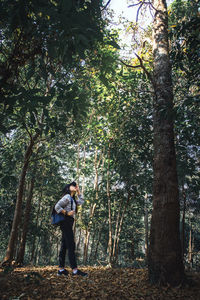 Full length of woman standing by tree in forest