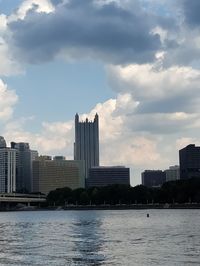 Modern buildings by river against sky in city