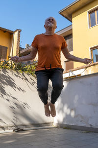 Full length of man skipping against built structure