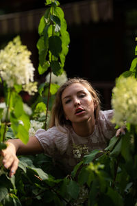 Portrait of young woman standing amidst plants