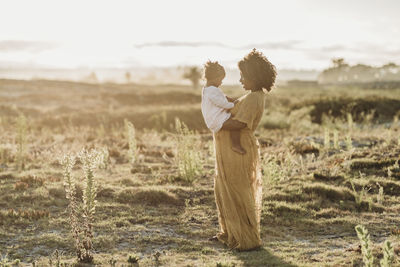 Full length view of pregnant mother holding young toddler girl on bell