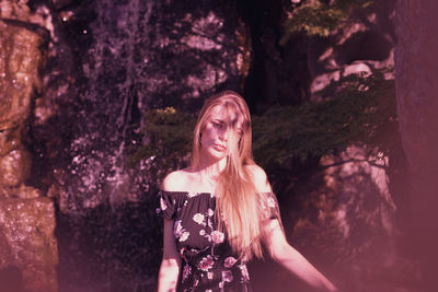 Portrait of young woman standing against trees