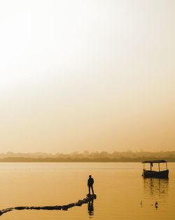 Silhouette man standing in sea against clear sky