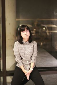 Portrait of sad young woman against glass window