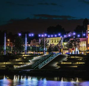 Illuminated bridge over river against sky at night