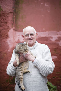 Portrait of senior man holding tabby cat