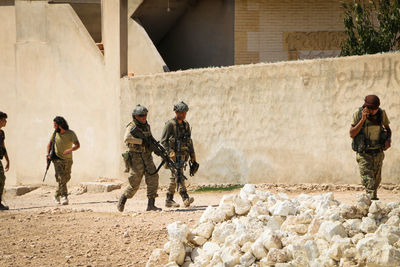 Full length of soldiers walking against building