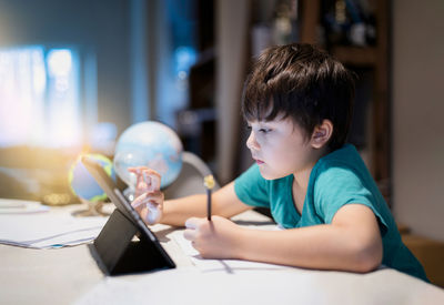 Portrait of boy sitting on table at home