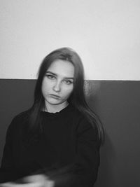 Portrait of young woman standing against wall