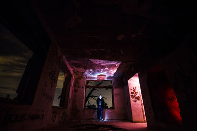 Rear view of woman standing in abandoned building