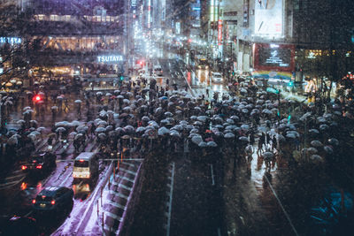 High angle view of people with umbrellas on street during rainy season at night