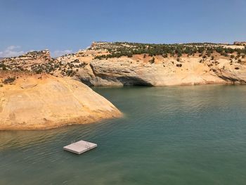 Scenic view of rocks by sea against sky