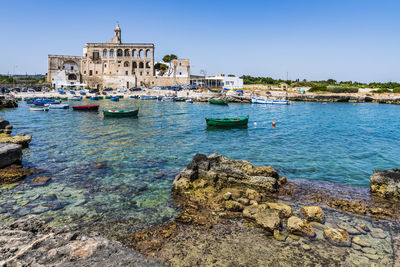 Sailboats in sea against buildings