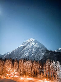 Scenic view of snowcapped mountains against clear blue sky at night