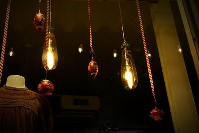 Low angle view of illuminated lighting equipment hanging from ceiling