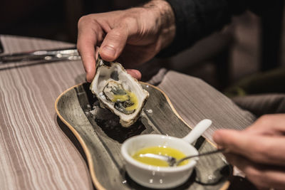 Cropped hands of person eating food at table