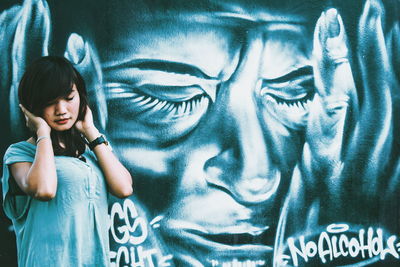 Woman standing against graffiti wall