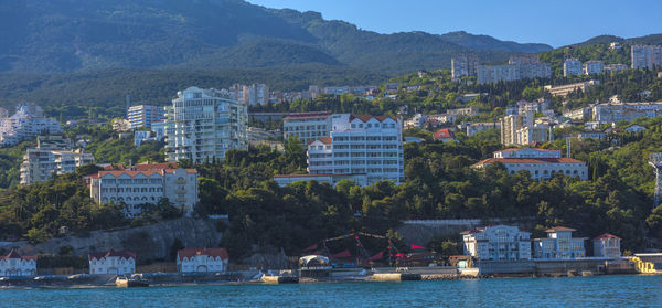 Sailboats in sea by buildings in city