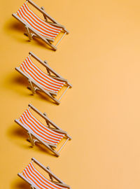 High angle view of deck chair on yellow background