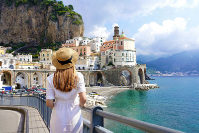 Rear view of woman standing by sea against sky