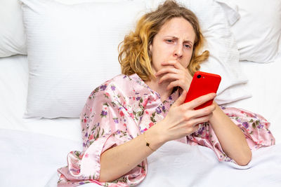 Young woman using mobile phone on bed