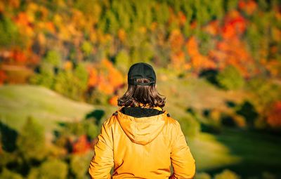 Rear view of man standing by trees in forest during autumn