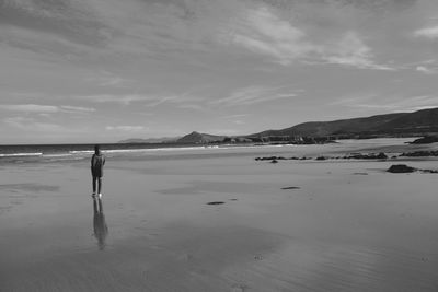 People on beach against cloudy sky